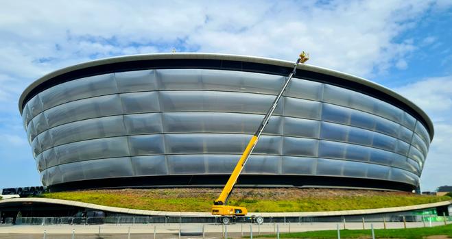 Men working on the roof of a modern spaceship-shaped building.