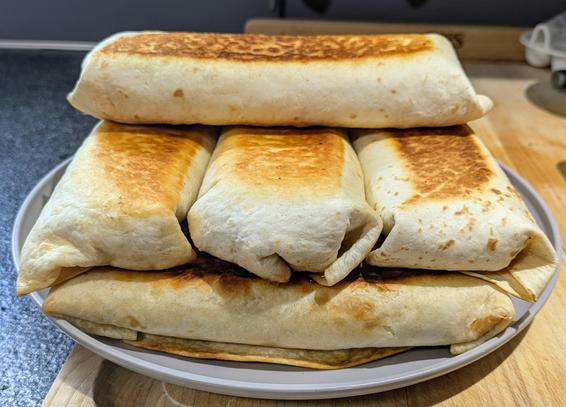 7 browned burritos stacked on top of each other like Jenga logs.