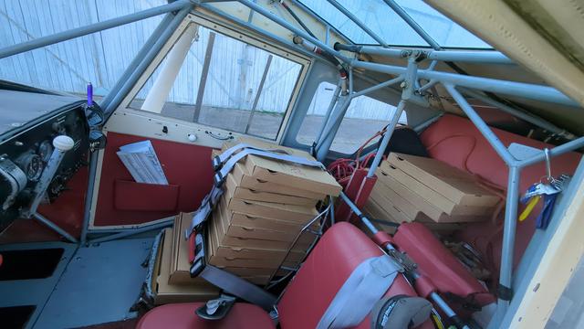 A lot of pizza boxes in small aircraft. In luggage department and on copilot seat. Also some salads and pasta.