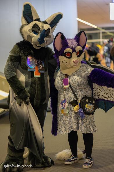 A photo of two bat fursuits standing next to each other.