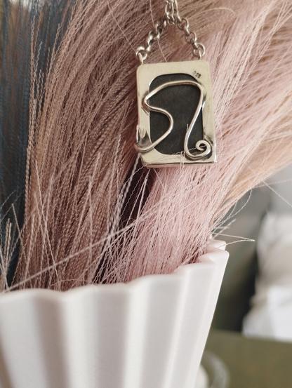 the back of the pendant. on the background a white base with grey plants