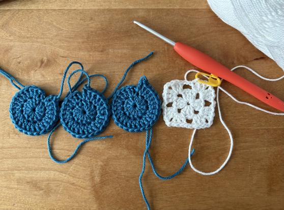 3 little crocheted rounds in petrol and 1 little crocheted square in white with a orange crochet hook