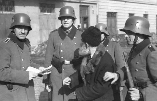 German Ordnungspolizei officers examining a man's papers in Nazi-occupied Poland, 1941