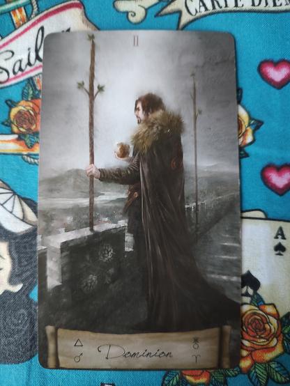 Card from the Heaven and Earth Tarot deck.
Two of Wands.
A man wearing a cloak with fur trim, holding a small globe in the right hand and a staff (wand) on the left. There is another staff nearby to his right. He is looking out from a castle's walls to the horizon.