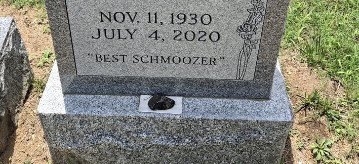 Picture of a Grey granite headstone with the inscription "best schmoozer"
