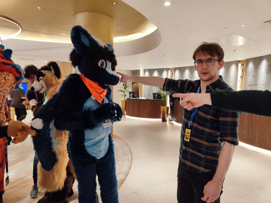 A blue fluffy dragon is pointed at by a group of people