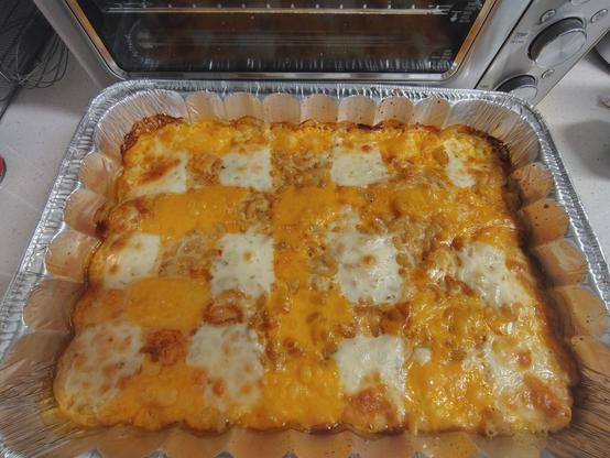 A checkerboard Trinidad macaroni pie in a disposable baking pan.