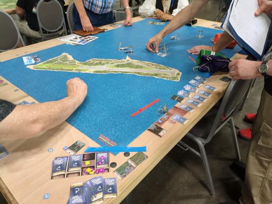 Wings of War setup taking up a 1m by 1.5m map which looks like a tiny island in the South Pacific. small WW2 era miniature planes are positioned on the map.