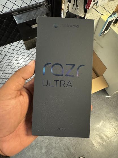 Human hand holding a black box from Motorola containing the Mororola Razr Ultra smartphone