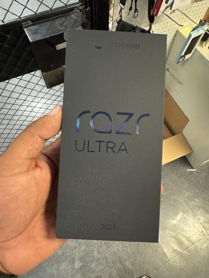 Human hand holding a black box from Motorola containing the Mororola Razr Ultra smartphone