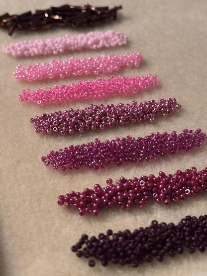 A line of seed bead piles in shades that ombre from pink to brown