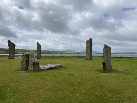 Stones of Steness. 4 tall standing stones in a circle under a cloudy sky. Smaller stones lie in the centre.