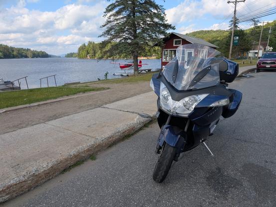 A motorcycle with a lake and docked seaplane in the background