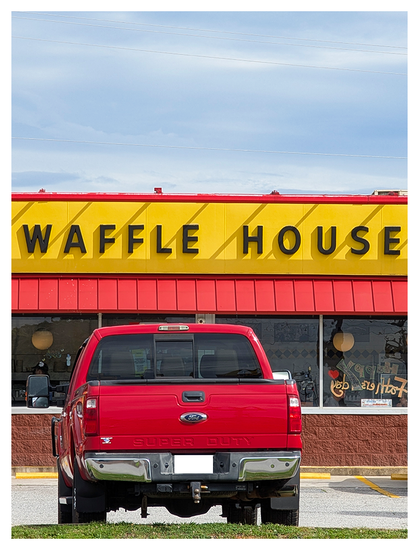rear view of a red ford pickup backed into a parking space at a waffle house, under a partly cloudy sky.