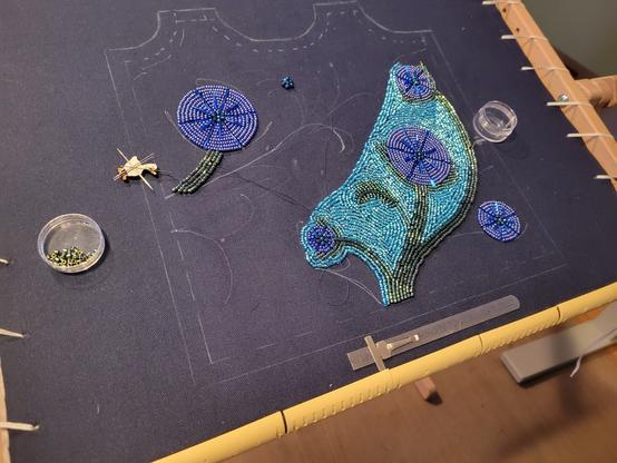 In progress beadwork. Flowers in dark blue, surrounded by sky blue sead beads.