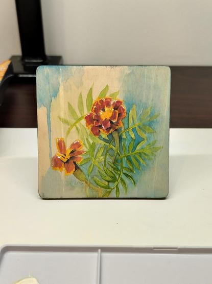 A 4 inch square painting of red and yellow flowers on wood