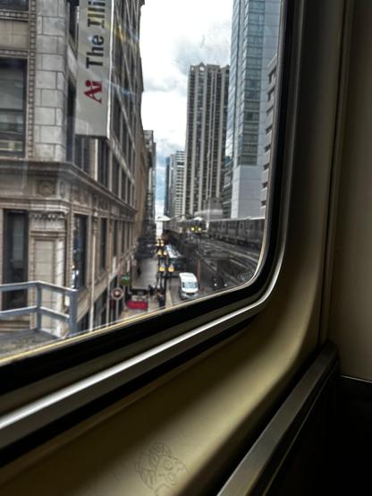 Riding the El train in the Chicago Loop and looking out the window at the train/tracks surrounded by high rise buildings