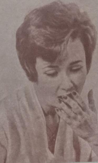 Mujer de los años 60 con una expresión pensativa y angustiada, cubriendo su boca con la mano, como si estuviera reflexionando sobre un tema serio.