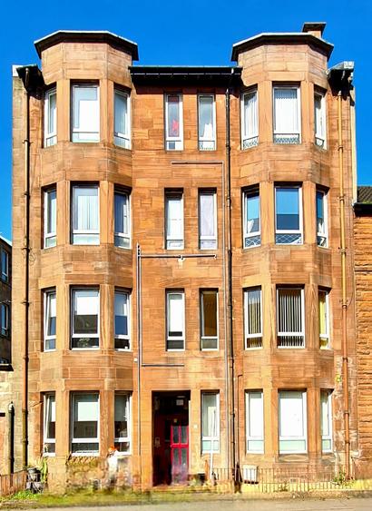 A narrow, red sandstone tenement in Glasgow.
