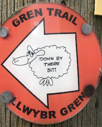 A red waymarking roundel with a white arrow pointing to the left, and a drawing of a sheep helpfully inscribed “DOWN BY THERE BUTT”. 

The “Gren Trail” is named after the cartoonist, who I mostly know from his Max Boyce album covers, but I think was a regular in the Western Mail.