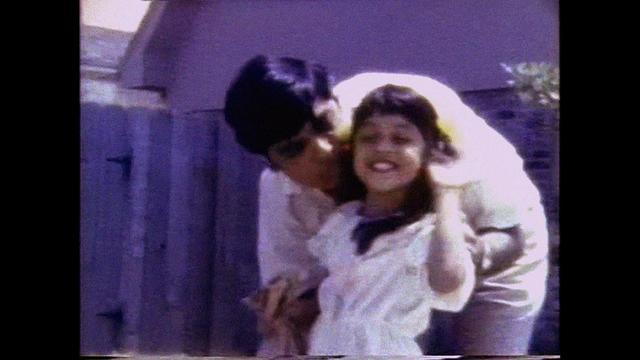 A dad and daughter smile in a still from a home video