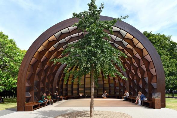 Photo looking north at this year's Serpentine Pavilion with Ginkgo tree in foreground. Designed by Marina Tabassum (b.1969, Dhaka, Bangladesh). Called 'A Capsule in Time', it is constructed of glulam and translucent brown polycarbonate panels. By the Serpentine South, City of Westminster, London.
