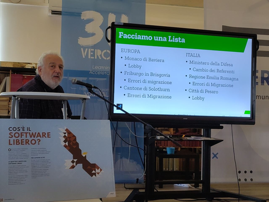 Il relatore Italo Vignoli fa una lista dei casi di totale insuccesso di adozione del software libero in Europa ed in Italia. In Europa sono elencate: Monaco di Baviera (per causa delle Lobby), Friburgo in Brisgovia (per errori di migrazione), il Cantone di Slolothurn (per errori di migrazione). In Italia, sono elencati: il Ministero della Difesa (per cambio dei referenti), la Regione Emilia Romagna (per errori di migrazione), e la città di Pesaro (causa Lobby).

In primo piano c'è un cartellone su Cos'è il Software Libero? Traduzione di Expolibre.org