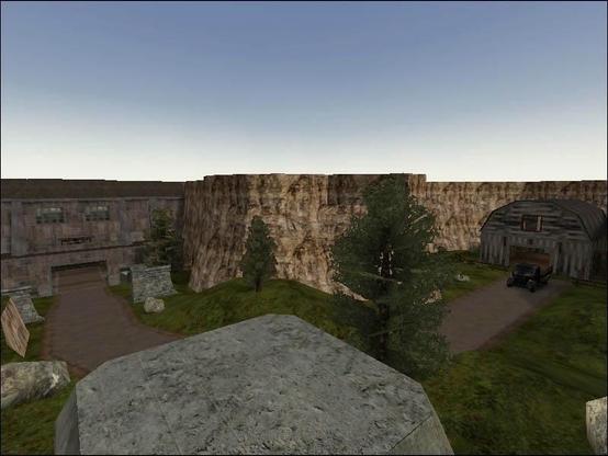 Screenshot of the starting area of Supply Depot, a popular competition map in Enemy Territory. A landscape featuring rugged cliffs, a cleared area with trees, and two structures, a barn with a truck, with a path leading to a fortified bunker.