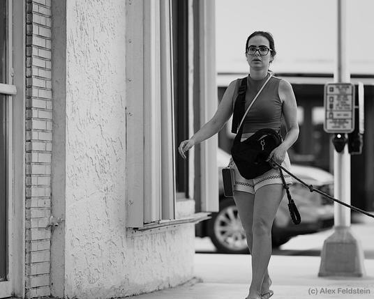 Woman walking past the camera with a dog on a leash (dog out of frame) (B&W)