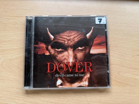 Disco Devil came to me de la banda Dover. Se ve la cara de un hombre con la cara roja y cuernos.