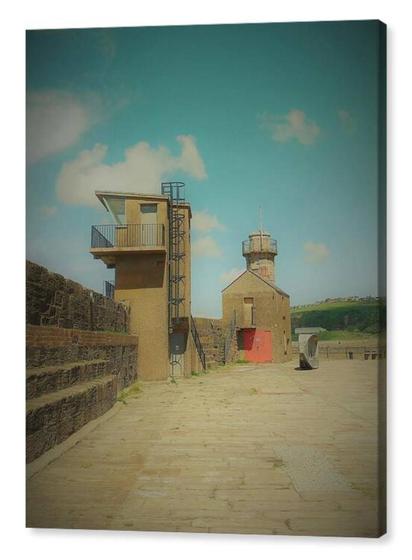 Colour portrait photograph showing three older buildings at the end of a pier beneath a blue sky.