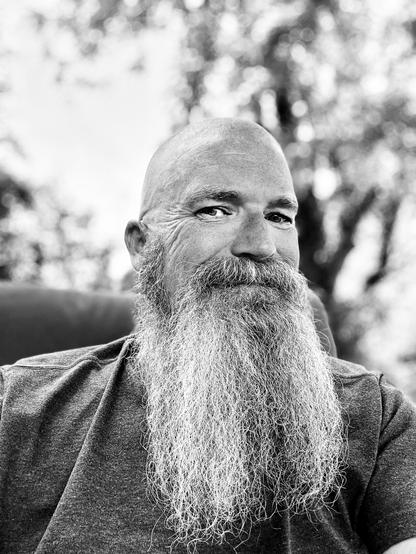 Portrait of a man with a long graying beard and a shaved head.