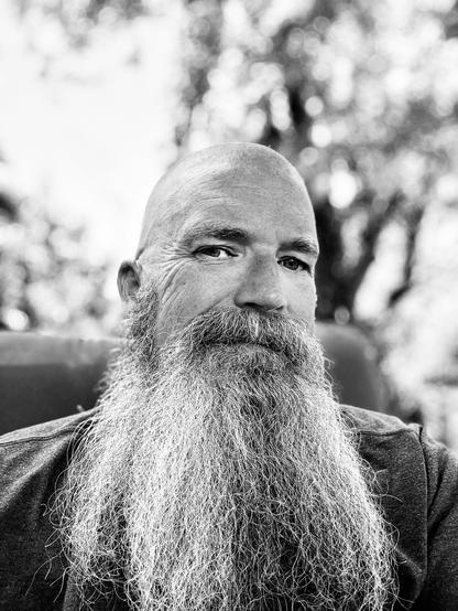 Portrait of a man with a long graying beard and a shaved head.