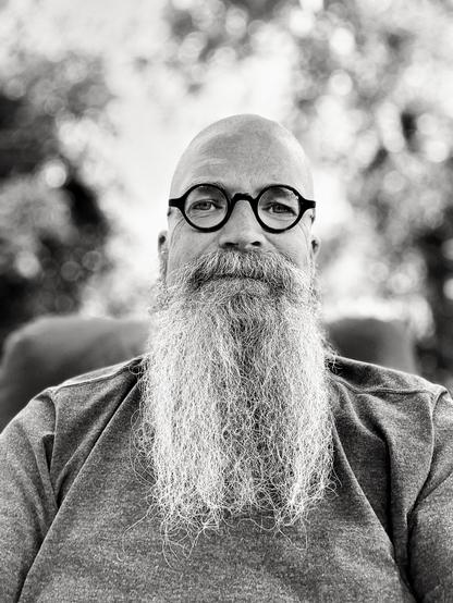 Portrait of a man with a long graying beard and a shaved head.
