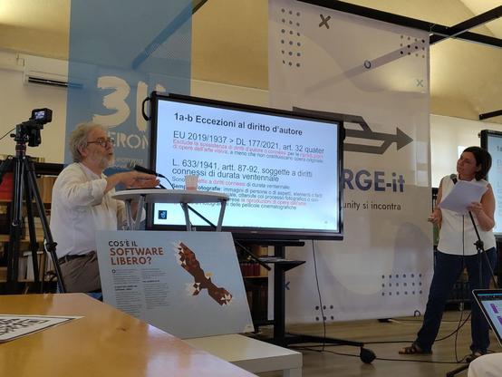 Andrea Brugnoli, sulla sinistra, seduto; Piergiovanna Grossi, sulla destra, in piedi, con una pagina di presentazione a proposito delle eccezioni al diritto d'autore.