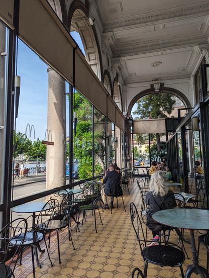 Must be the nicest McDonald I've ever seen. No gaudy colours (logo rendered in white only), dainty metal tables and bent-iron chairs. People sitting under an extended decorated roof, by the lake side.