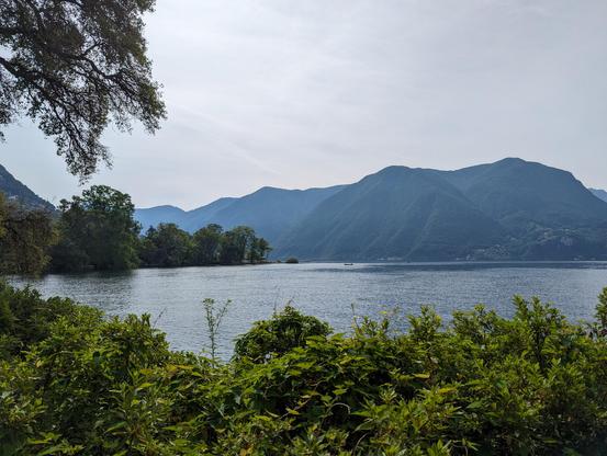 Another view over the lush almost tropical plants by the side of the lake. The lake view extends to the other side of the post-glacial deep valley. The air is slightly hazy.