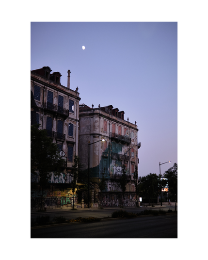 two residential buildings in lisbon in the evening with graffiti and a big mural of a crocodile, moon shining from above in misty violet sky
