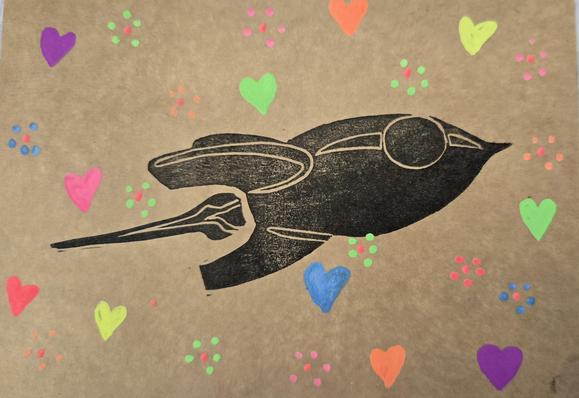 A postcard of the fairydust rocket stamped in black ink. Around the rocket are many hearts and flowers in neon colors.