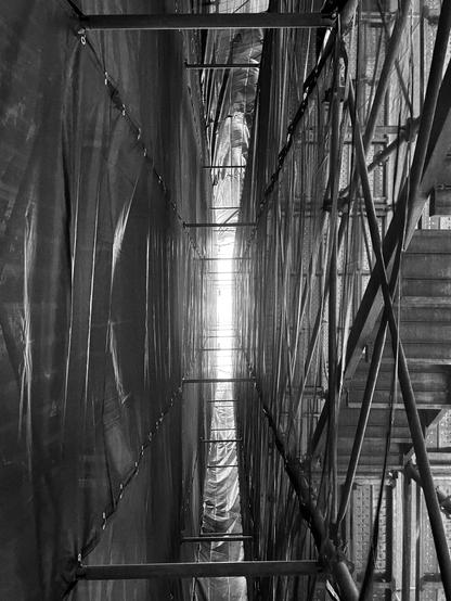 Narrow space between the scaffolding and the building in black and white.