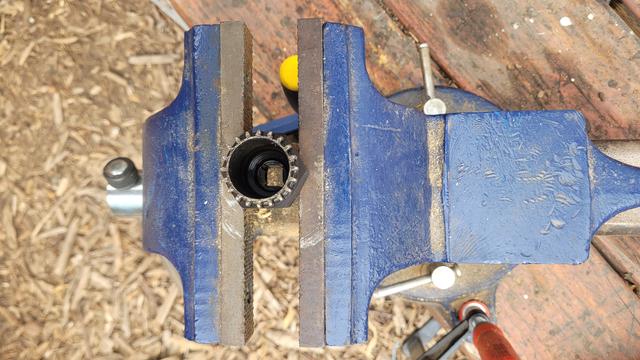 Large heavy bench vise clamped to a wood deck and a Park Tool bottom bracket wrench clamped on