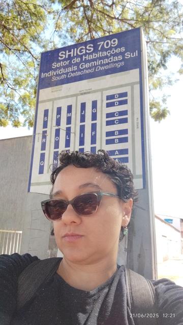 Mulher usando óculos de sol escorada na placa do Setor de Habitações Individuais Geminadas Sul 709, Asa Sul, Brasília, DF, Brasil.