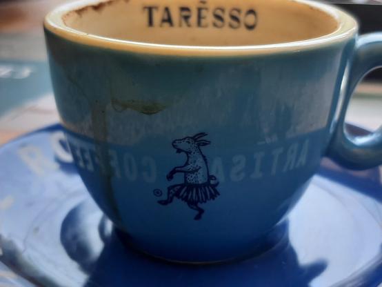 A small blue coffee cup featuring an image of a dancing goat