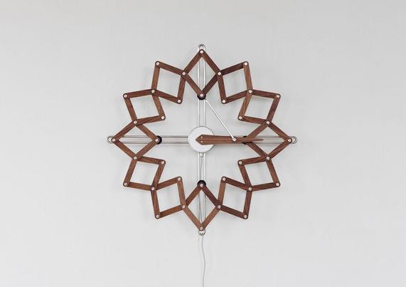 A unique wall clock featuring a geometric design with wooden frames, set against a light textured background.