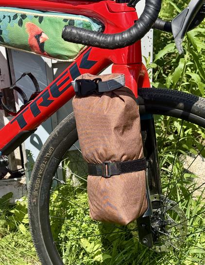 A stuff sack with a few shirts and shorts packed inside and strapped to 3d printed fork cage. You can also see my experimental frame back sewn from a black oil sunflower seed bag with Cardinal on the side. This is all on a red Trek Checkpoint