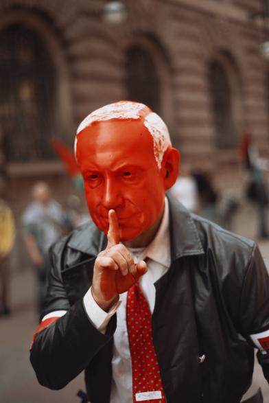 Someone wearing a red netanyahu mask as a symbolic protest.