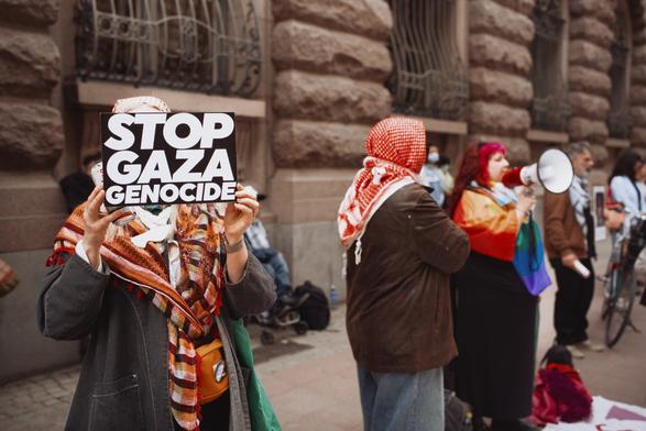 One person with a placard saying "Stop genocide" and we can see others in the background in the protest.