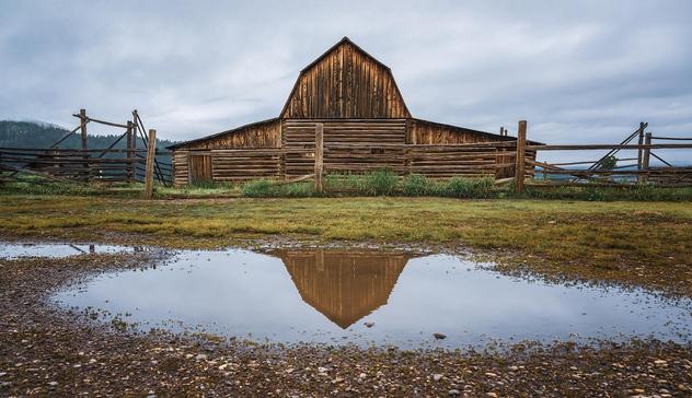 Reflection of one of the Moulton Barns in Grand Teton NP in a puddle in the road.