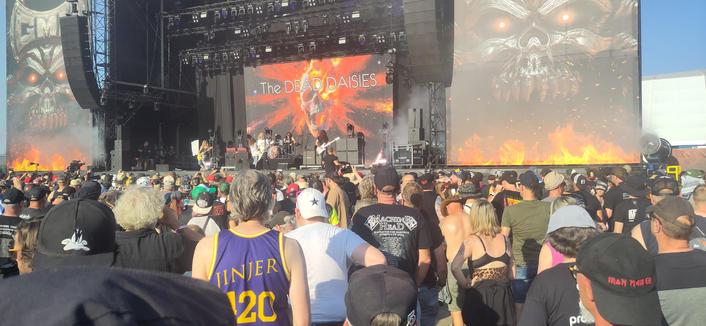 The DEAD DAISIES op het Jupiler-podium op Graspop 2025. Op de achtergrond een schedel waarvan het linkeroog ontploft, met daaroverheen hun naam. Op de voorgrond publiek.