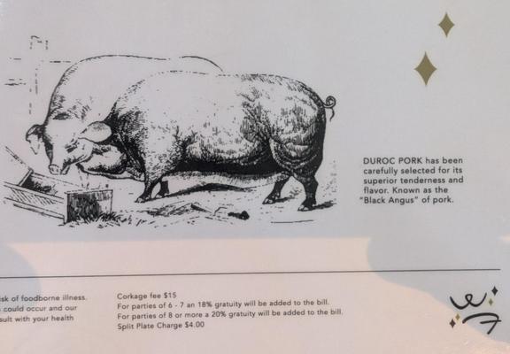 Restaurant menu with an illustration of two pigs and a description saying Duroc pork is the "Black Angus" of pork.